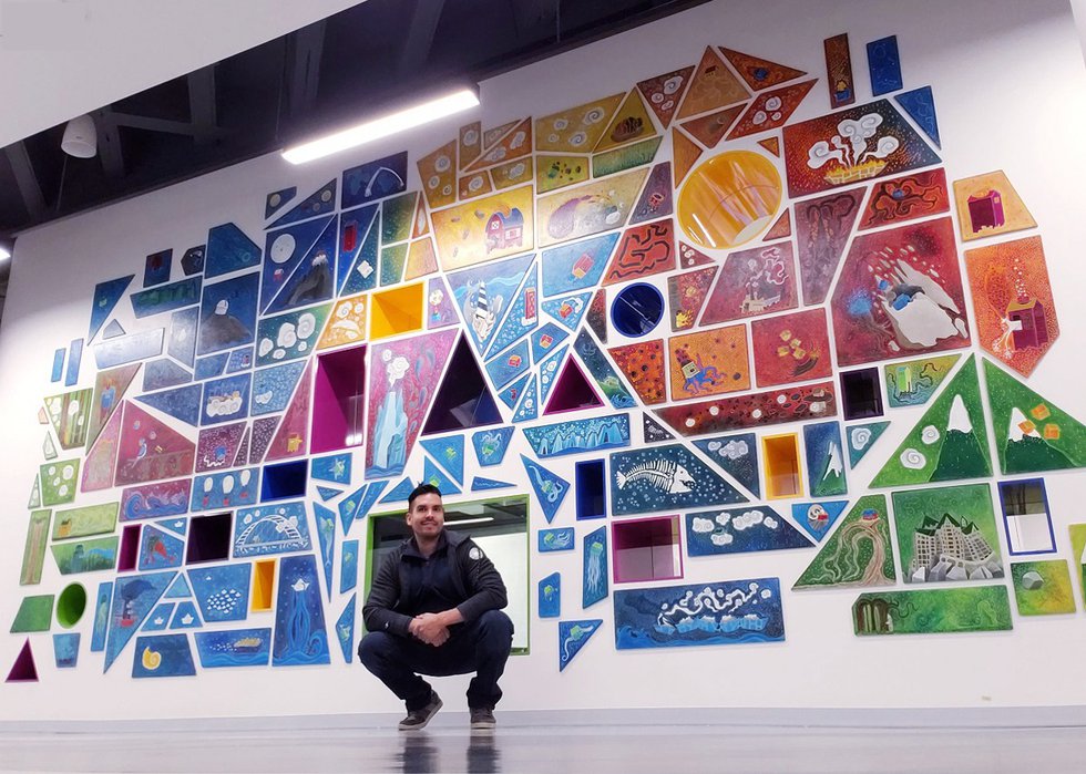 Ricardo Copado poses with his mural at Edmonton's downtown public library. (courtesy the artist)