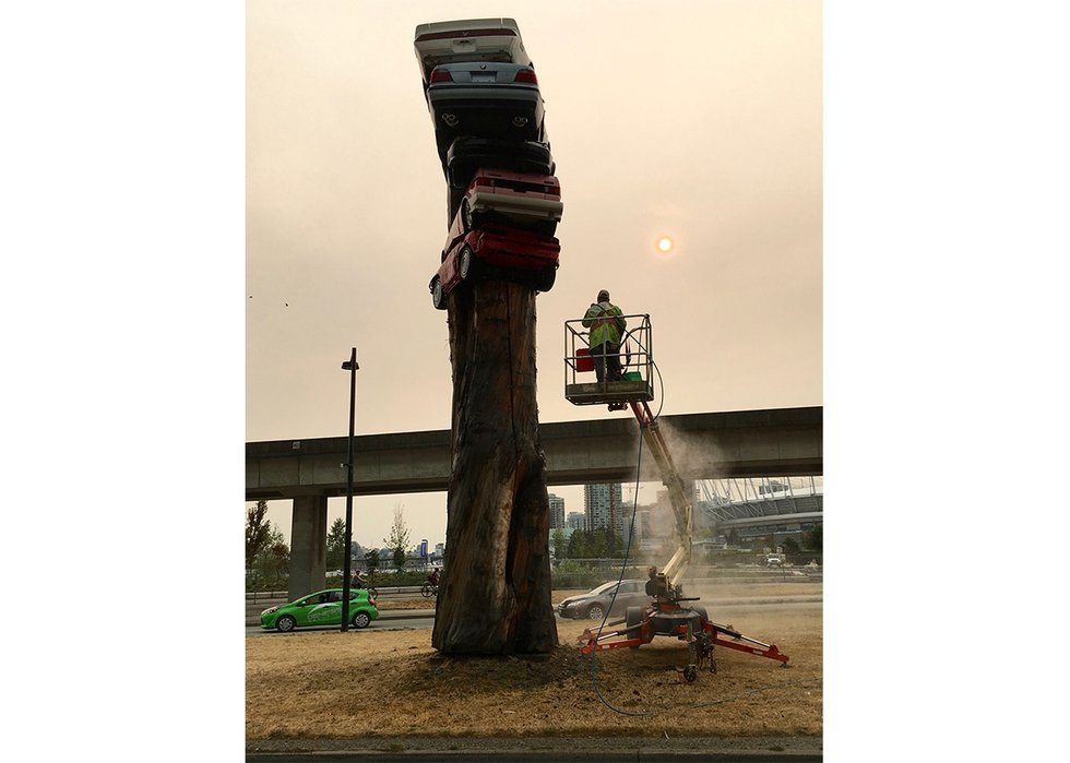 Marcus Bowcott's photograph, “Smoke Event, 2018,”  shows a worker cleaning “Trans Am Totem” while smoke from wildfires obscures the sky. (courtesy of artist)