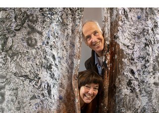 Liz Ingram and Bernd Hildebrandt peek out from behind a work at their exhibition, "Touching Gravitas," at the SNAP gallery in Edmonton. (photo by Manpreet Singh)
