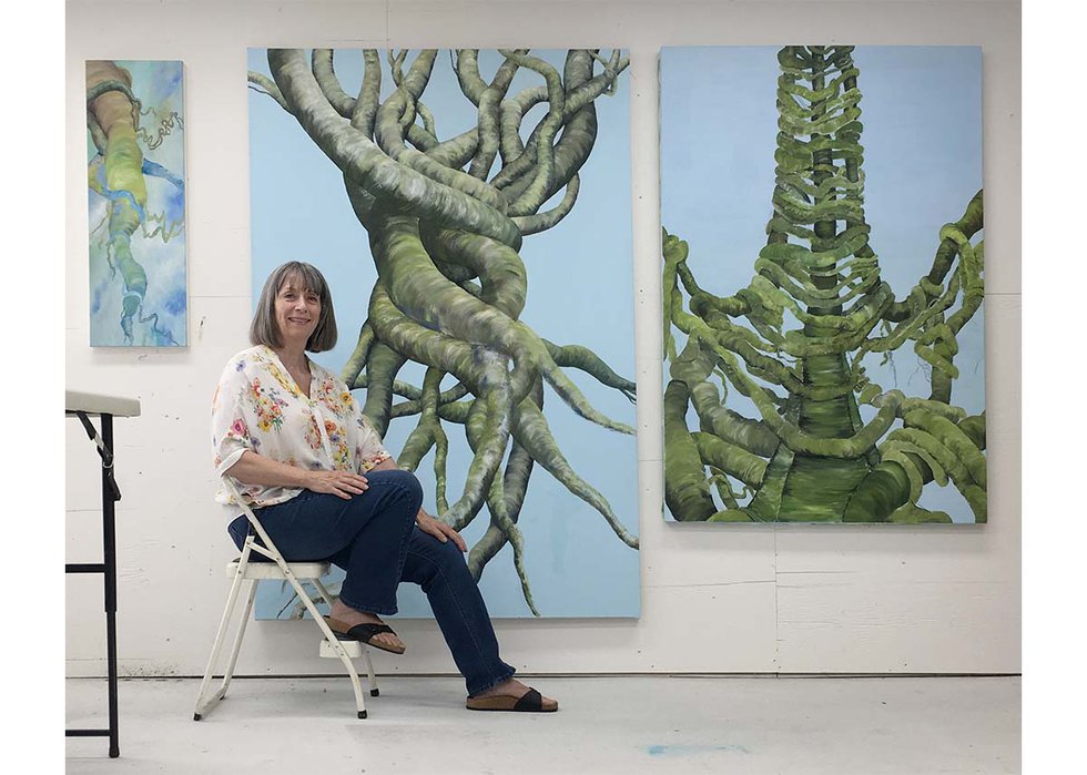 Lynn Christine Kelly poses with three unfinished oil paintings from her "Connections" series. (photo by Albert Chow)