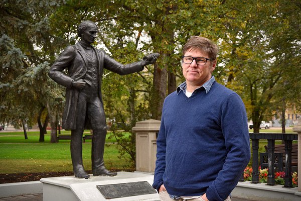 James Daschuk, author of “Clearing the Plains,” stands in front of a statue of Sir John A. Macdonald on the University of Regina campus. (courtesy University of Regina)