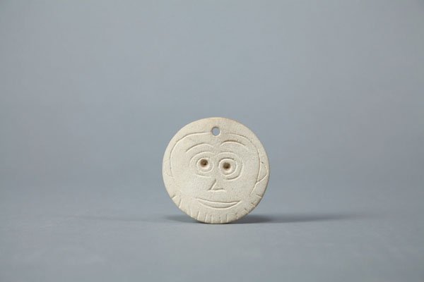 "Carved bone depicting a happy face"